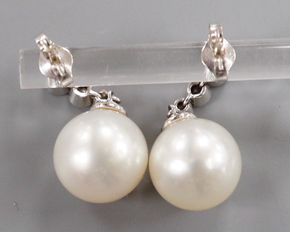 A modern pair of 750 white metal, singe stone South Sea pearl and graduated three stone diamond set drop earrings, overall 22mm, gross weight 6.8 grams